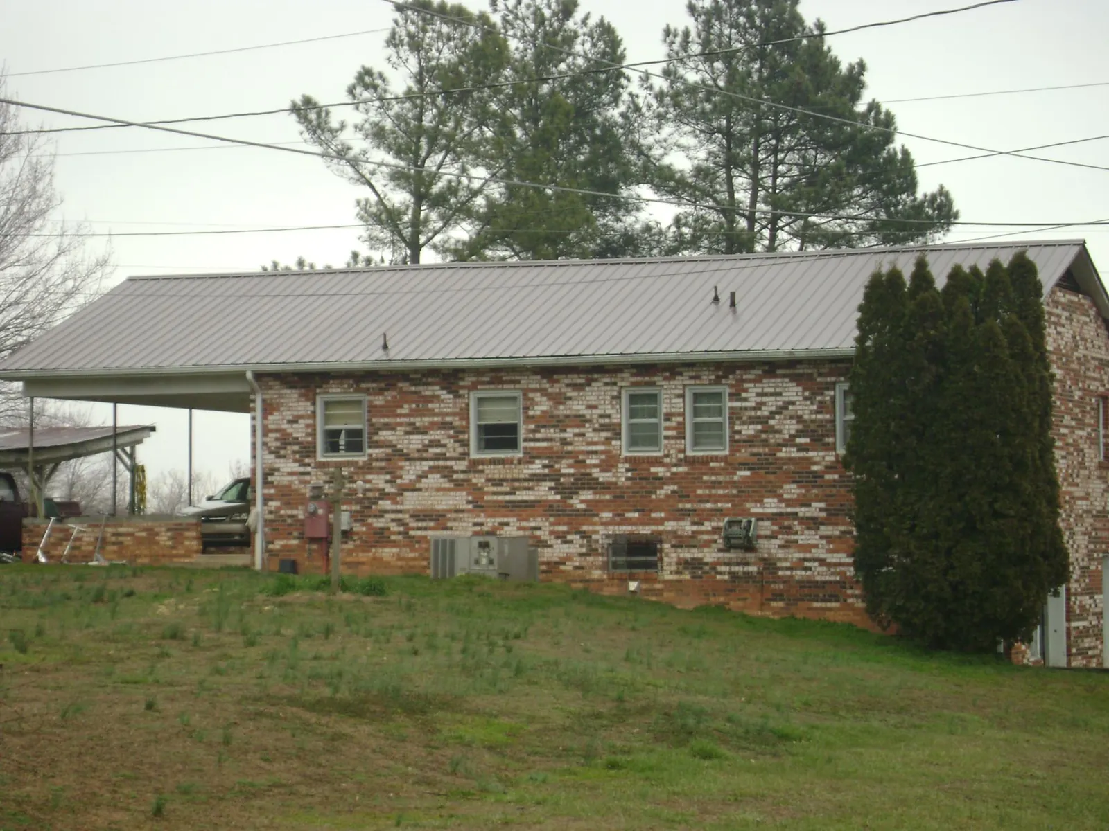 Gray metal roof on a brick split level home with a carport in Manchester
